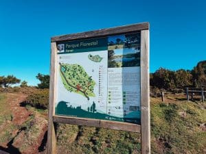 Tablica informacyjna Parque Florestal Fanal na tle błękitnego nieba i lasu til