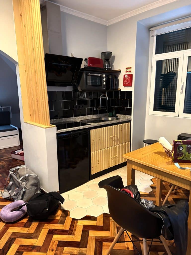 Aneks kuchenny z czarnymi szafkami, mikrofalówką i stołem przy oknie w apartamencie ASPA Studios