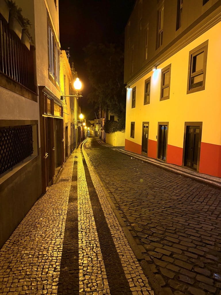Pusta brukowana uliczka w Funchal nocą w świetle latarni