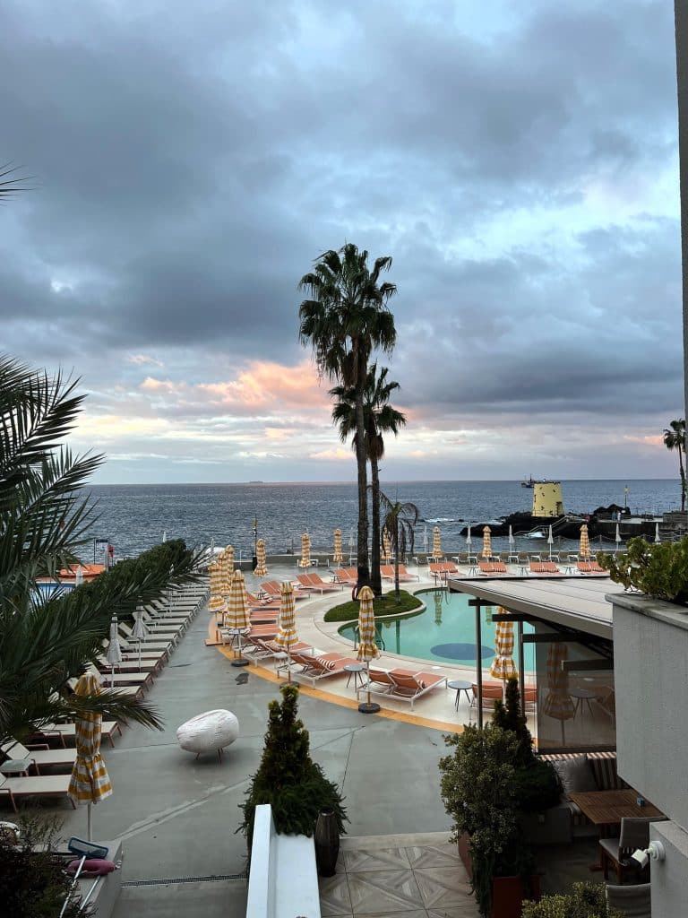 Baseny i palmy przy hotelu NEXT w Funchal o świcie, w tle ocean