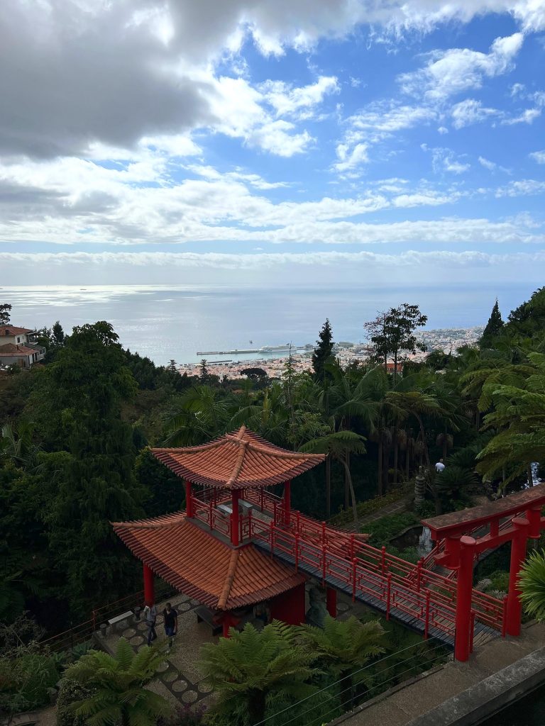 Czerwona pagoda i mostek w ogrodzie orientalnym Monte Palace, w dali Funchal i ocean pod chmurami