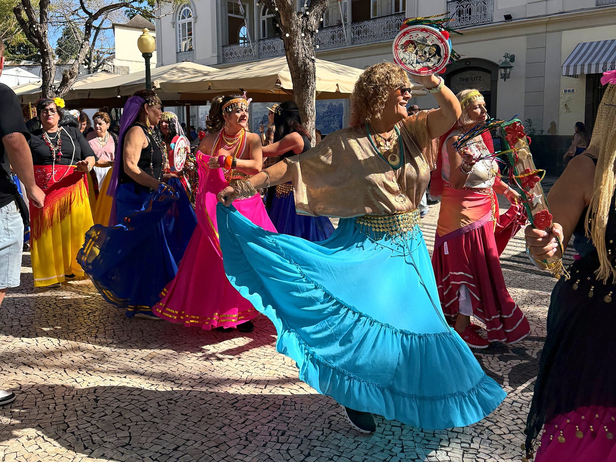 Tancerki w kolorowych spódnicach wirują w tańcu podczas Carnaval Solidário na Avenida Arriaga w Funchal