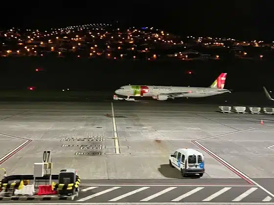 Samolot TAP na płycie lotniska Madera nocą, w tle światła domów na zboczu