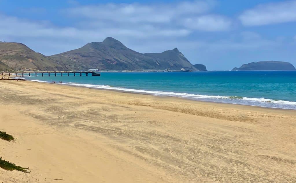 Szeroka piaszczysta plaża Porto Santo z molo i wysepką Ilhéu de Baixo w tle