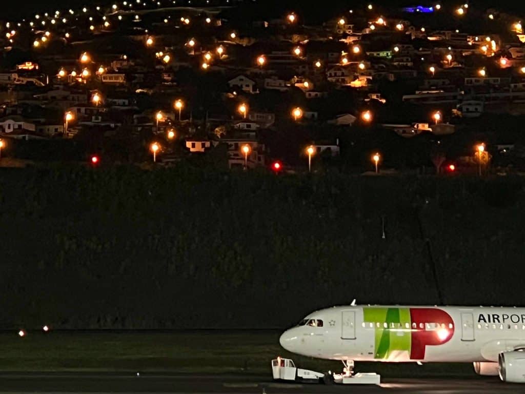 Samolot TAP Air Portugal na lotnisku Madera nocą na tle oświetlonego zbocza