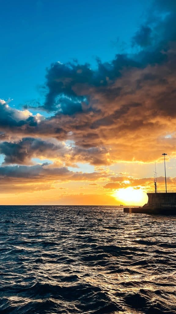 Zachód słońca nad oceanem i chmury widziane z pokładu w drodze do portu w Funchal