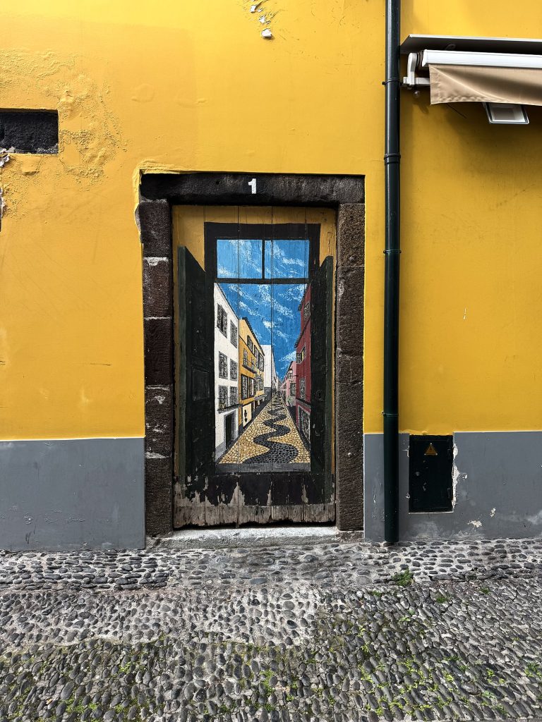 Malowane drzwi na żółtej fasadzie w Zona Velha w Funchal